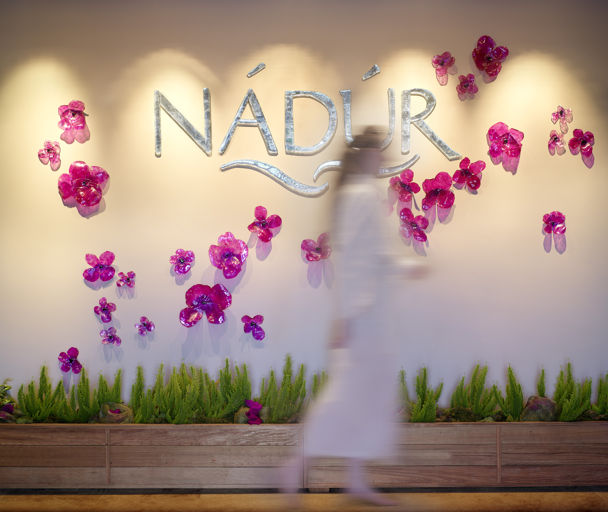 A blurred person walks past a wall with the word 